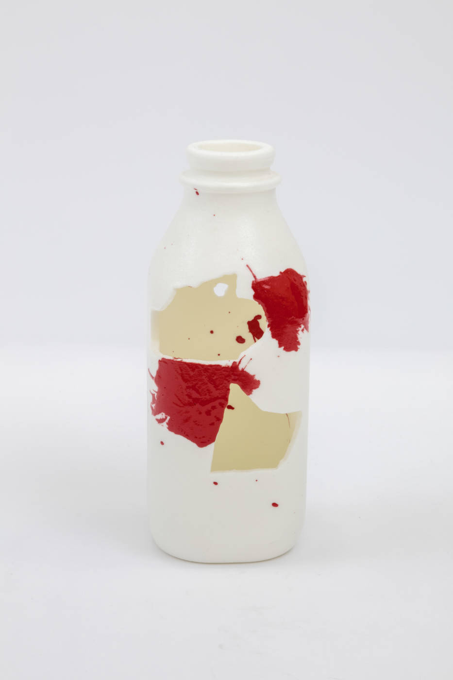 Bottle sculpture with splashes of cream and red color