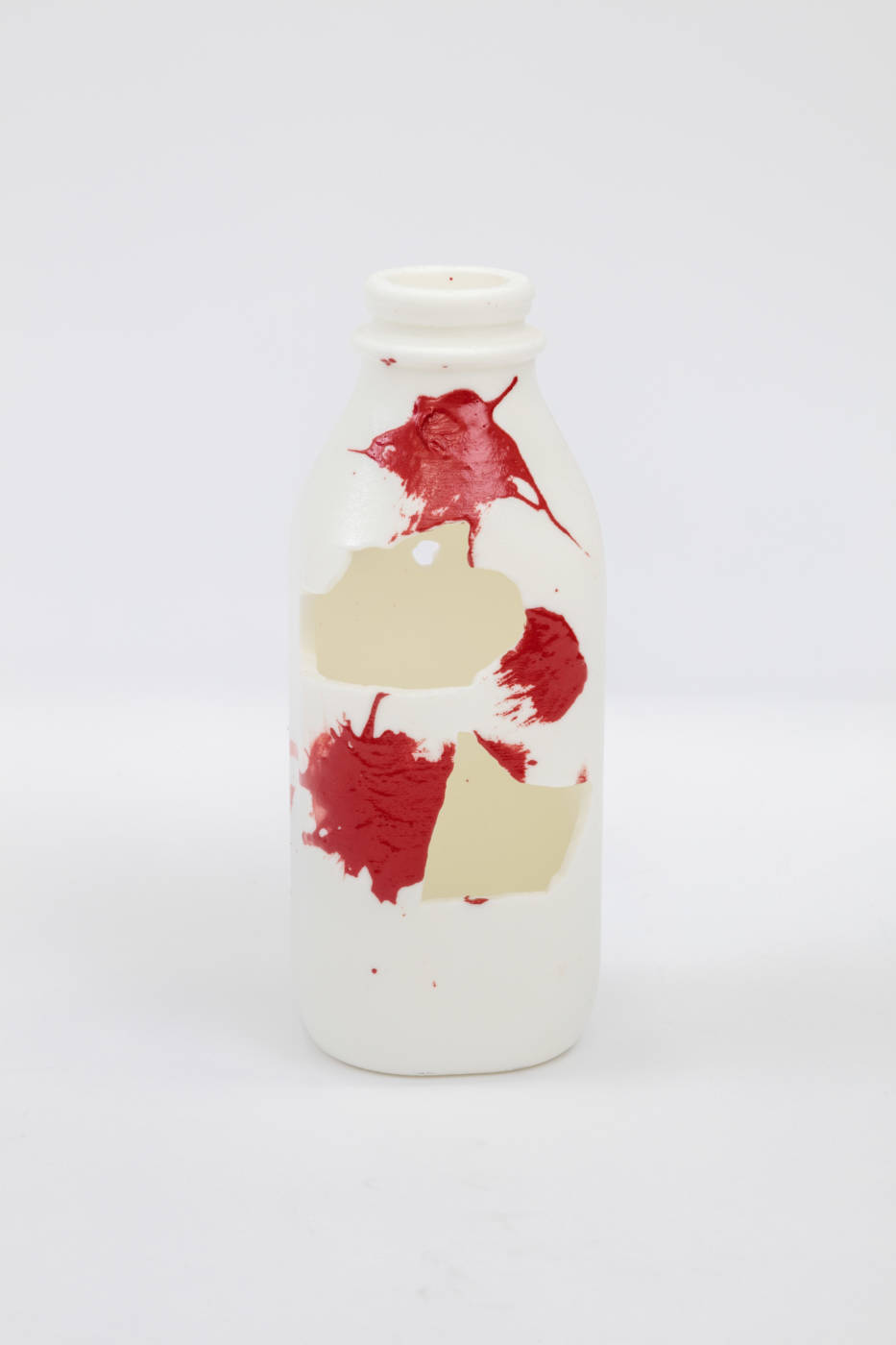 Bottle sculpture with splashes of cream and red color