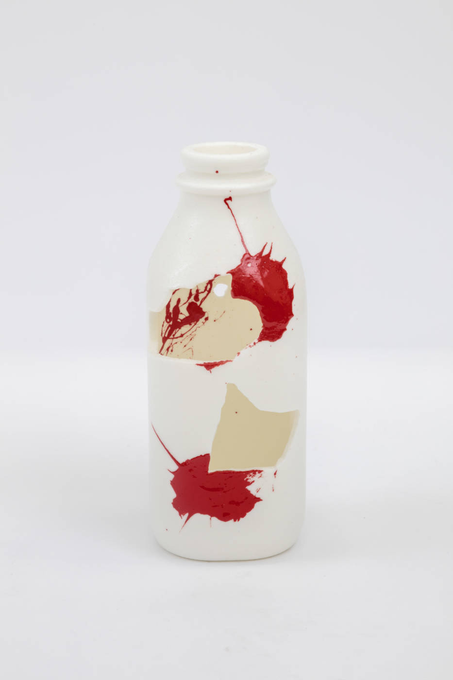 Bottle sculpture with splashes of cream and red color